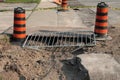 two orange and black traffic delineator pylon barrel drums next to sidewalk