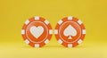Two Orange Casino Chips with Heart and Spade Symbols on Yellow Background gambling poker Royalty Free Stock Photo