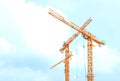 Two orange crane in cross on blue sky Royalty Free Stock Photo