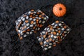 Two orange and cream colored pumpkin patterned fabric face masks, with a ceramic pumpkin, on a black background