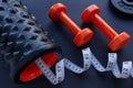 Two orange dumbbells with black bumpy foam roller and white tape measure Royalty Free Stock Photo