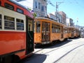 Two Orange historic streetcar of the F-Line MUNI Train and two other trains parked on street