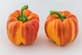 Two orange and red "enjoya" bell peppers (capsicum) on white background Royalty Free Stock Photo