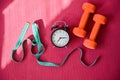 Two orange tunnels measuring tape and alarm clock on a pink yoga mat. Time to do fitness on and lose weight by the Royalty Free Stock Photo