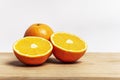 Two oranges bursting with vitamin c, one cut in half and one whole on a bamboo board with a white wall background Royalty Free Stock Photo