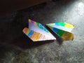 two origami planes made of colored paper, lying on the floor near the door