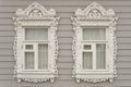 Two ornamental windows with carved frame of traditional russian rural wooden house. Royalty Free Stock Photo