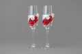 Two ornate wedding wine glasses decorated with red and pink roses.