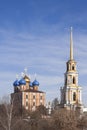 Two orthodox churches against a cloudy blue sky with some leafless trees on the bottom of the frame. A cube red brick building Royalty Free Stock Photo