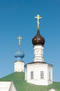 Two orthodox golden bright shiny crosses are on top of the black and blue cupolas of white old stone church with a green roof Royalty Free Stock Photo