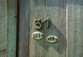 Two oval metal plates with nubers thirty one and nineteen and number thirty one nailed on wood door