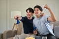 Two overjoyed Asian male friends celebrated their game wins while playing video games together Royalty Free Stock Photo