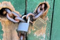 Two Padlocks and Chain on Green Doors With Worn Paint Royalty Free Stock Photo