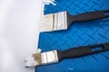 Two paint brushes on a blue plastic tray with white paint