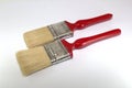 Two paint brushes 2 inches wide with red handles on a wooden background Royalty Free Stock Photo