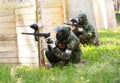 Two paintball players behind wooden fortifications