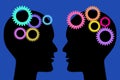 Two painted silhouette heads facing each other with colorful gears isolated on blue background. Think and communication concept.