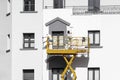 Two painters painting the facade of the building with paint rollers