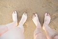 Two pairs of feet, male and female crossed on a sea beach sand. Concept of summer vacation Royalty Free Stock Photo