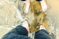 Two pairs of feet in the sand of the sea