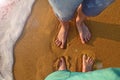 Two pairs of feet stand on the sand and wait for the wave to come. wave on sandy beach of Kalutara, Sri Lanka Royalty Free Stock Photo