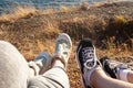 Two pairs of female legs in sports sneakers on the seashore. Female feet seen from above