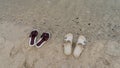 Two pairs of flip-flops are standing on the sand of the beach. Royalty Free Stock Photo