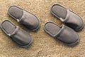 Two pairs of gray homemade slippers isolated on a brown background. Royalty Free Stock Photo