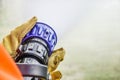 Two pairs of hands holding the handle on the end of a fire fighters water hose spraying water during practice