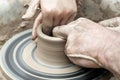 Two pairs of hands mold something from clay on a potter`s wheel