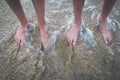 Two pairs of kids feet on the sand in the water .Family on vacations. Royalty Free Stock Photo