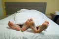 Two pairs of legs in bed under a white blanket. Male and female lying feet on red bed together Royalty Free Stock Photo