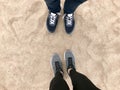 Two pairs of legs in sneakers shoes stand opposite each other against the background natural loose yellow golden warm beach sand Royalty Free Stock Photo