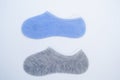 Two pairs of new short socks of blue and gray color are lying on a white background. View from above