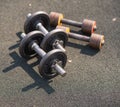 Two pairs of old dumbbells lie on the floor on a sports field on the street