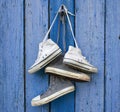 Two pairs of old worn textile sneakers hang on a nail