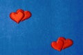 Two pairs of red hearts on cardboard background of classic blue color