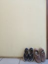 Two pairs of shoes leaning against the cream wall