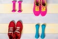 Two pairs of sports shoes and a dumbbell on a wooden background