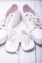 Two pairs of sports shoes on a white wooden background. The shoes of father and son or daughter. Fathers day concept Royalty Free Stock Photo