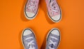 Two pairs of textile sneakers on an orange background stand opposite each other. Dialogue and confrontation concept Royalty Free Stock Photo