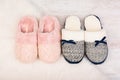 Two pairs of warm female slippers on white furry carpet