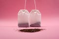 Two paper bags with tea and with a bunch of black loose tea on a pink background close-up Royalty Free Stock Photo