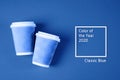 Two paper coffee cups on blue background