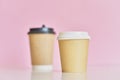 Two paper coffee cups on pink background. Creative mockup image