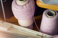 Two paper cone with pink purple cashmere silk wool string on table and knitting machine part equipment. DIY handmade hobby craft