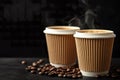 Two paper cups filled with hot coffee releasing steam, set against a black background Royalty Free Stock Photo