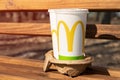 Two paper cups from McDonald`s staying in the cardboard carrier on the bench in park.