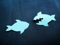 Two paper fish, one of them is a predator as a concept of aggression or conflict. Royalty Free Stock Photo