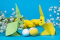 Two paper origami bunnies and an Easter eggs on a blue background. Crafts with your own hands for Easter Royalty Free Stock Photo